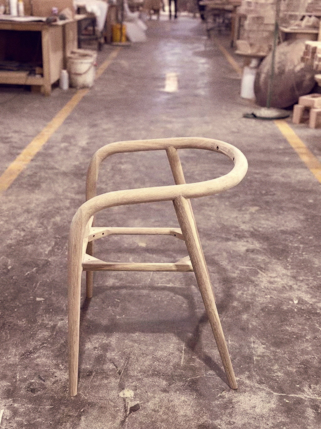 A raw oak Yume chair frame standing unfinished on the factory floor