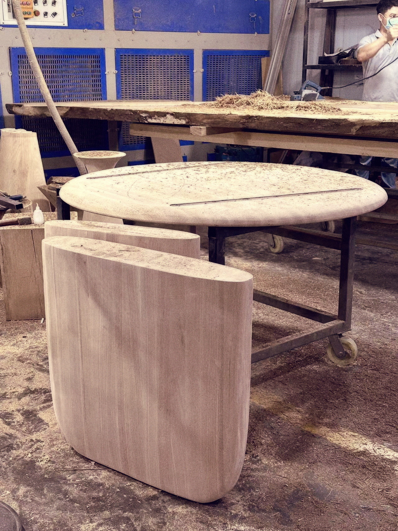 A craftsman hand-planing a tabletop, wood shavings falling from the bench
